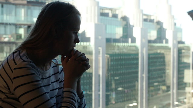 Sad woman being deep in thoughts and then looking out the window