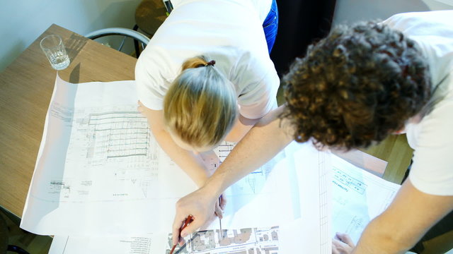 Male and female architects during work with construction schemes