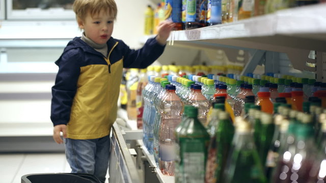 Little boy in the shop putting mineral water into the basket