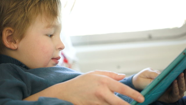 Boy in the train using touchpad held by mother