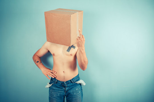 Man with cardboard box on head displaying obscene gesture
