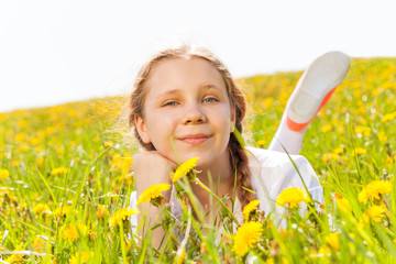 Smiling charming girl laying in dandelion  meadow