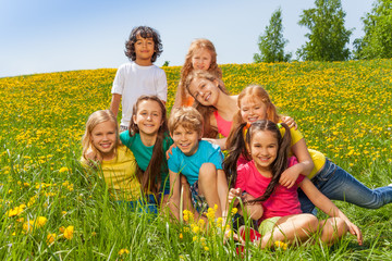 Fototapeta premium Smiling kids sitting together on the green grass