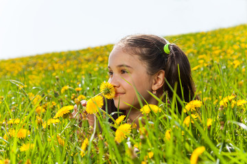 Smiling girl smelling dandelion in the meadow