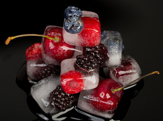 Fresh fruits frozen in ice cubes isolated on black background.