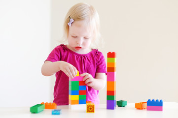 Cute toddler girl plaing with colorful blocks