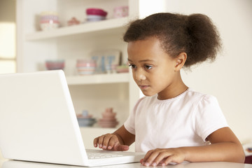 Young girl working on laptop at home