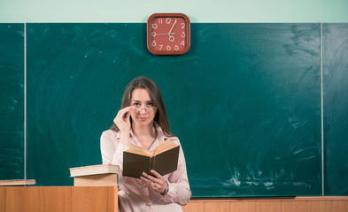 young teacher at blackboard with open book
