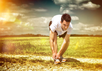 Athlete pausing to tie his laces on a morning run