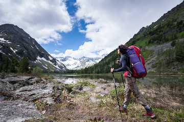 Hiker is walking by mountain lake in Altai mountains, Russia