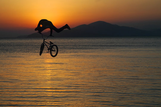 Silhouette of a man doing a jump with a bmx bike