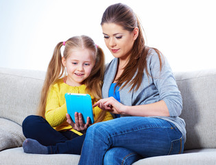 Mother with daughter sitting on sofa home work learning.