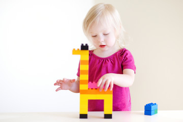 Cute toddler girl playing with colorful blocks