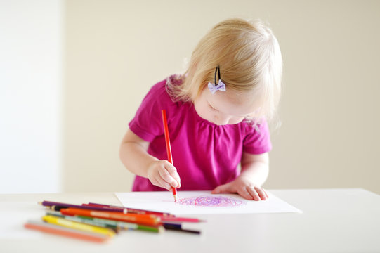 Cute toddler girl drawing with colorful pencils