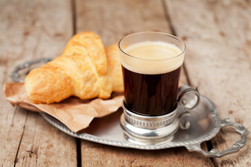 Coffee and croissants on tray on wooden background