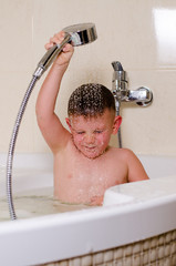 Cute small boy showering in the bath