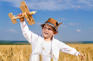 Little boy flying a toy plane in a wheat field