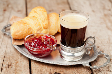 Coffee and croissants on tray on wooden background