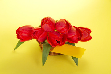 Bouquet of red tulips in a basket and card