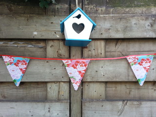 A birdhouse hanging on a fence with garlands. Concept for celebrating a new home
