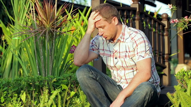 Sad man sitting in the garden in exotic place