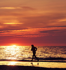 Woman running at beautiful sunset in the beach.