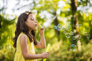Little girl blowing soap bubble