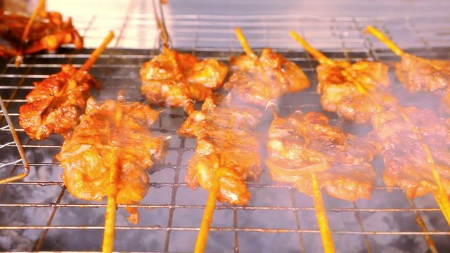 Close up frying pieces of meat in the grill on wooden sticks