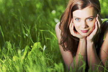 Naklejka na ściany i meble Woman laying in a green field