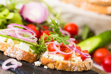 Open sandwiches with feta cheese, vegetables and onion rings.