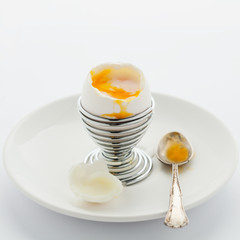Soft boiled egg in egg cup on white background