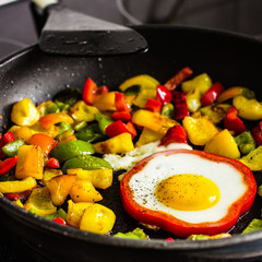 Fried egg in red pepper ring and coloful vegetables.