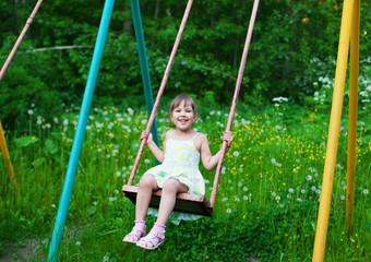 Little beautiful girl swinging in park