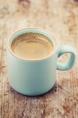 Cup of coffee on wooden table, toned