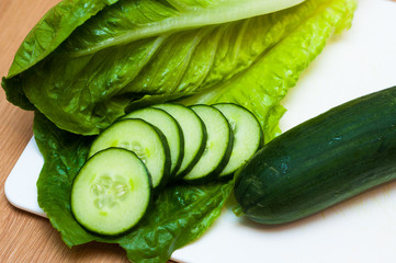 Close up of whole cucumber and slices on a chopping board