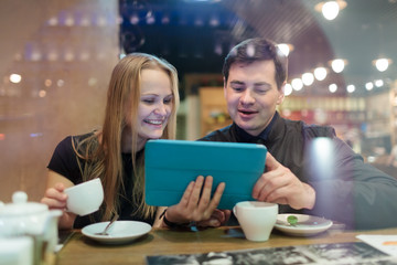 Young people drinking coffee and looking on pad