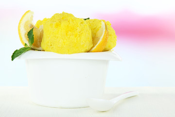 Tasty ice cream scoops in bowl, on wooden table