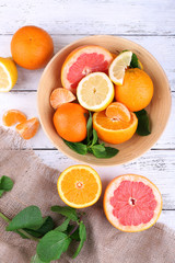 Fresh citrus fruits with green leaves in bowl