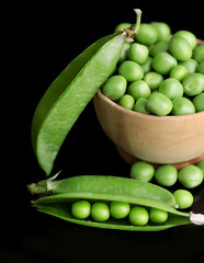 Fresh green peas in bowl isolated on black background