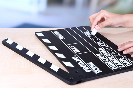 Black cinema clapper board in hands, close up