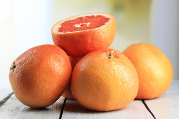 Ripe grapefruits on wooden board, on bright background