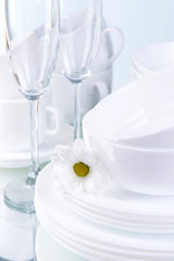 Set of white dishes on table on light background