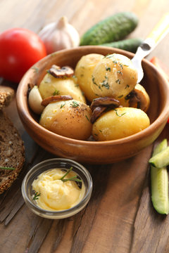 Young boiled potatoes in bowl on wooden table, close up