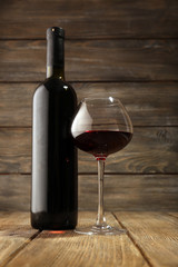 Bottles of wine with glass on wooden background