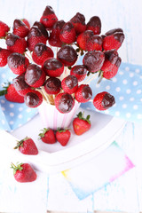 Strawberry in chocolate on skewers in cup on table close-up