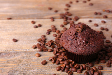 Chocolate muffin and coffee grains on wooden background