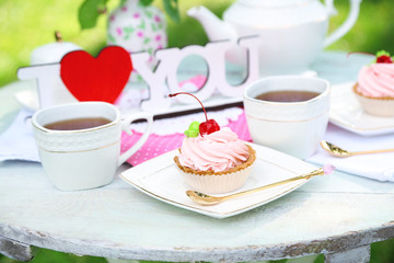 Tasty cake and cup with tea on table, close-up, outdoors