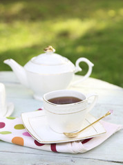 Teapot and cup on table, close-up, in garden