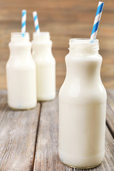 Milk in bottles with paper straws on table