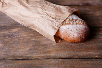 Loaf in paper bag on wooden background